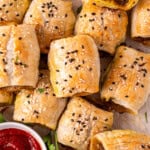 The beef sausage rolls on a tray with tomato sauce.