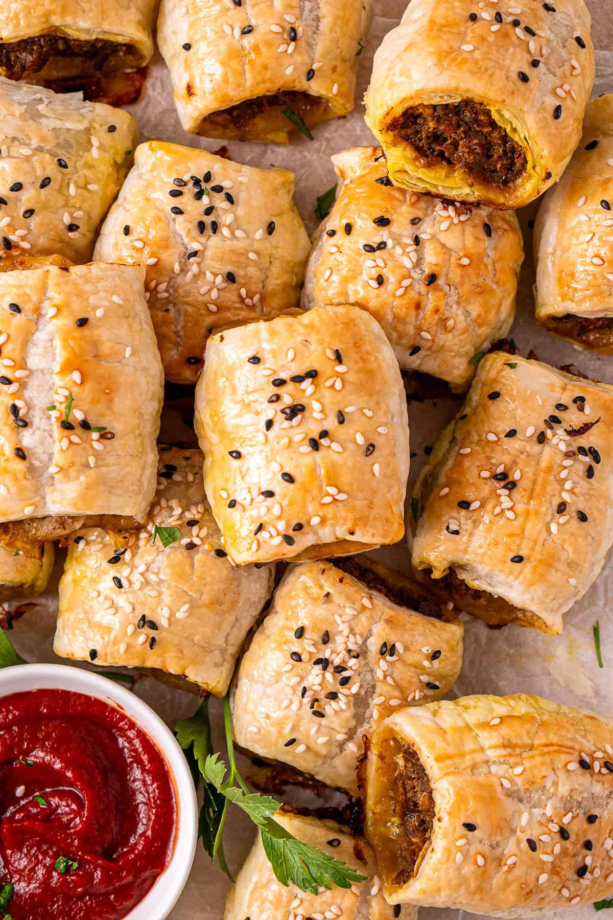 The beef sausage rolls on a tray with tomato sauce.