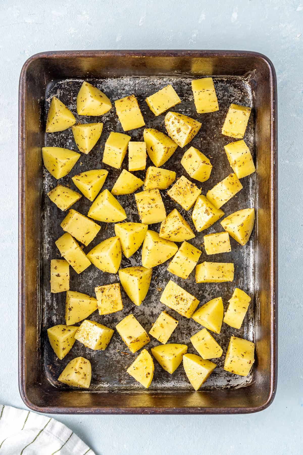 The seasoned potatoes on a baking tray.