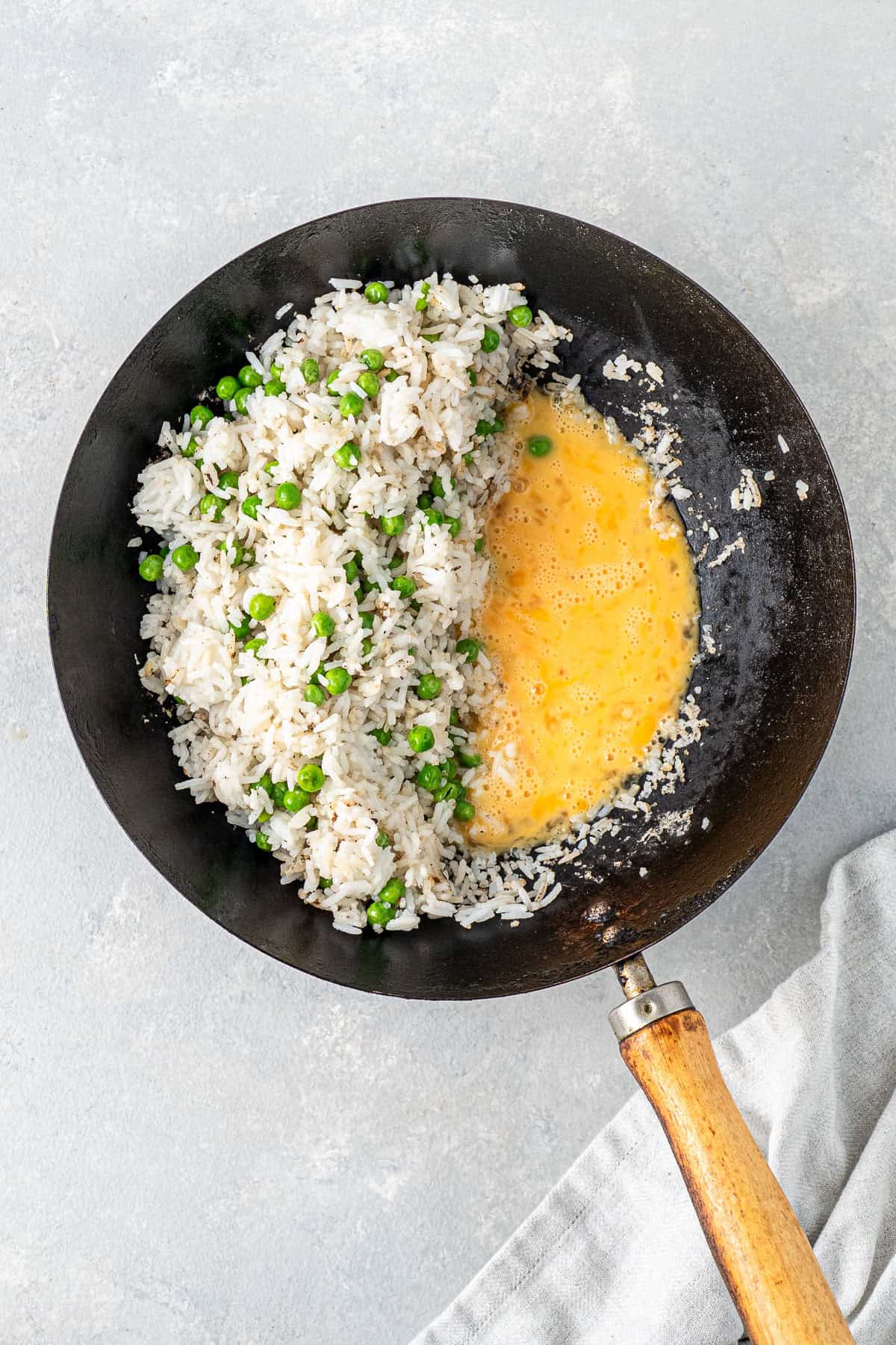 Adding the eggs to cook in the wok with the rice and peas.