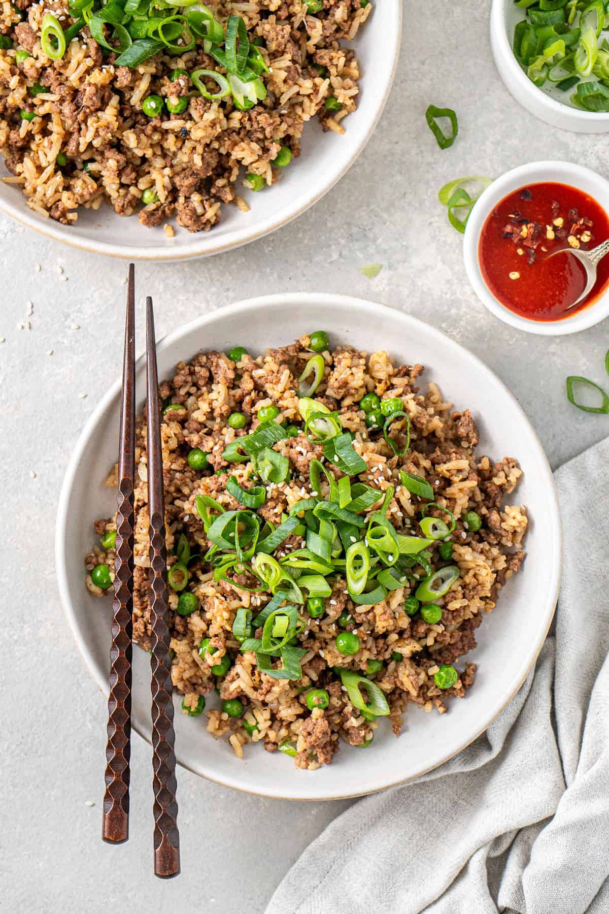 Ground beef fried rice served into bowls with spring onions and chopsticks.
