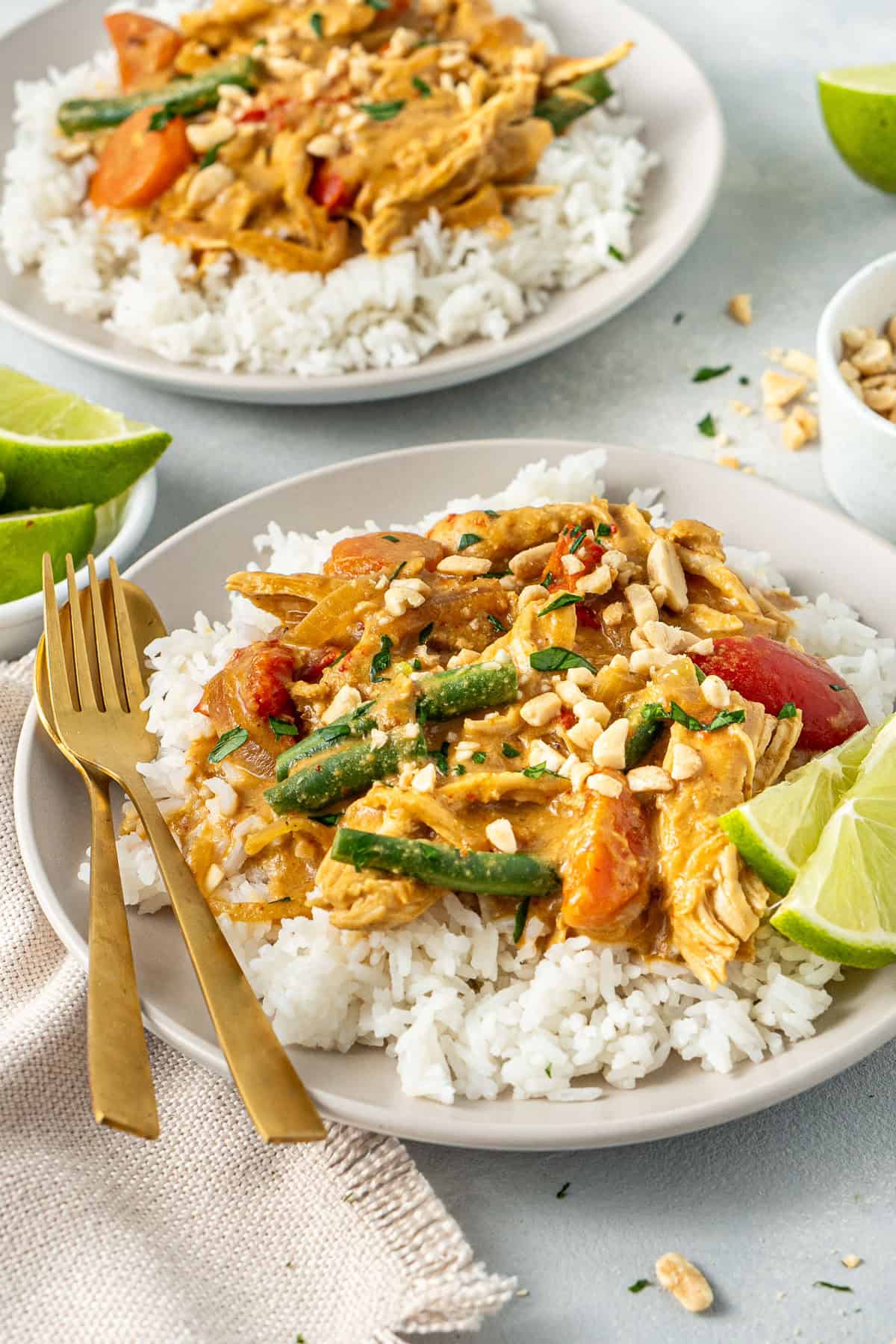 Satay chicken with rice and fresh lime served on a plate with cultlery.