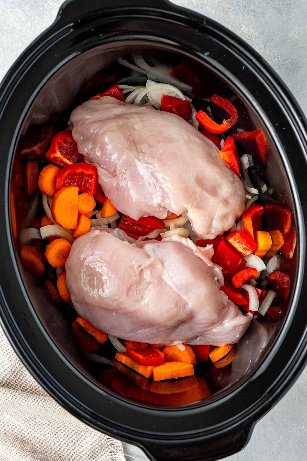 The onion, carrot, capsicum and chicken breast in the slow cooker.