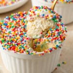 A spoon taking a bite of a dot cake with ice cream.