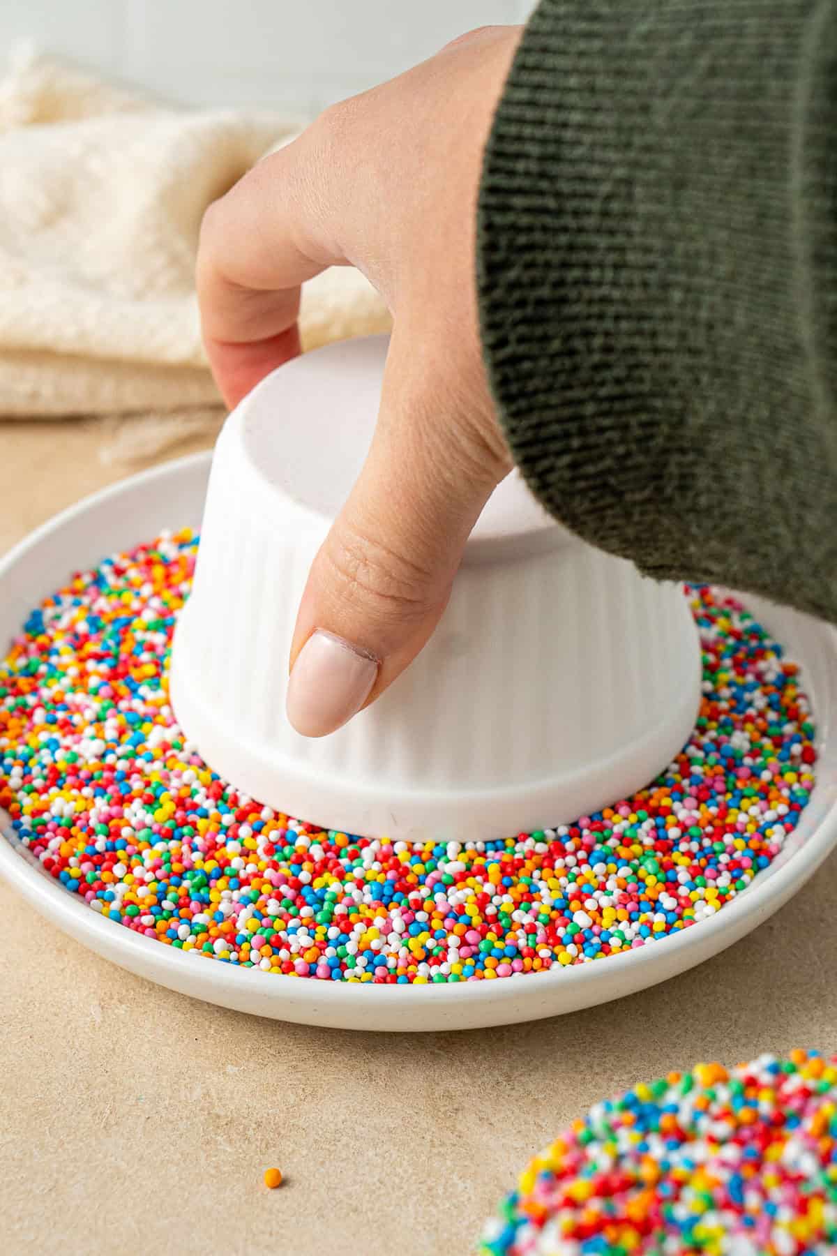 Dipping the chilled cakes into a plate of sprinkles.