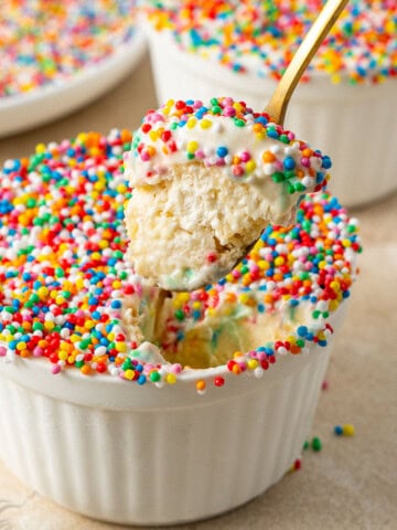 A spoon taking a bite of a dot cake with ice cream.