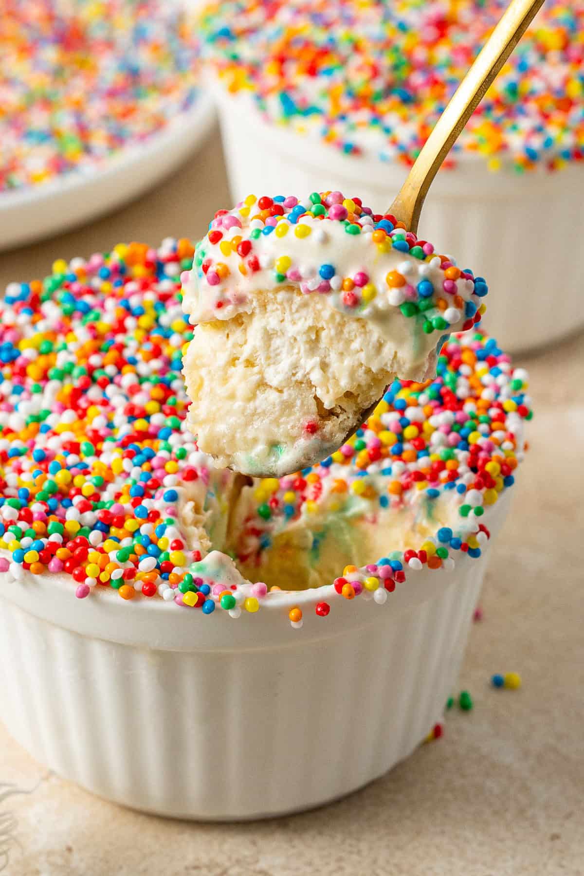 A spoon taking a bite of a dot cake with ice cream.
