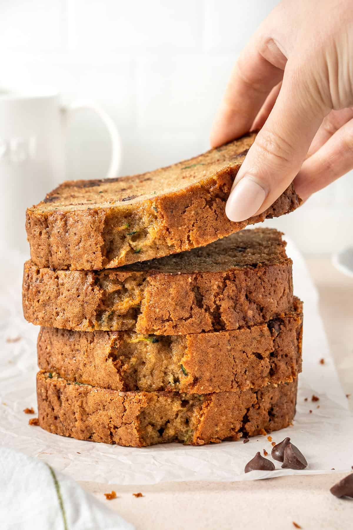 A hand picking up a slice of zucchini bread.