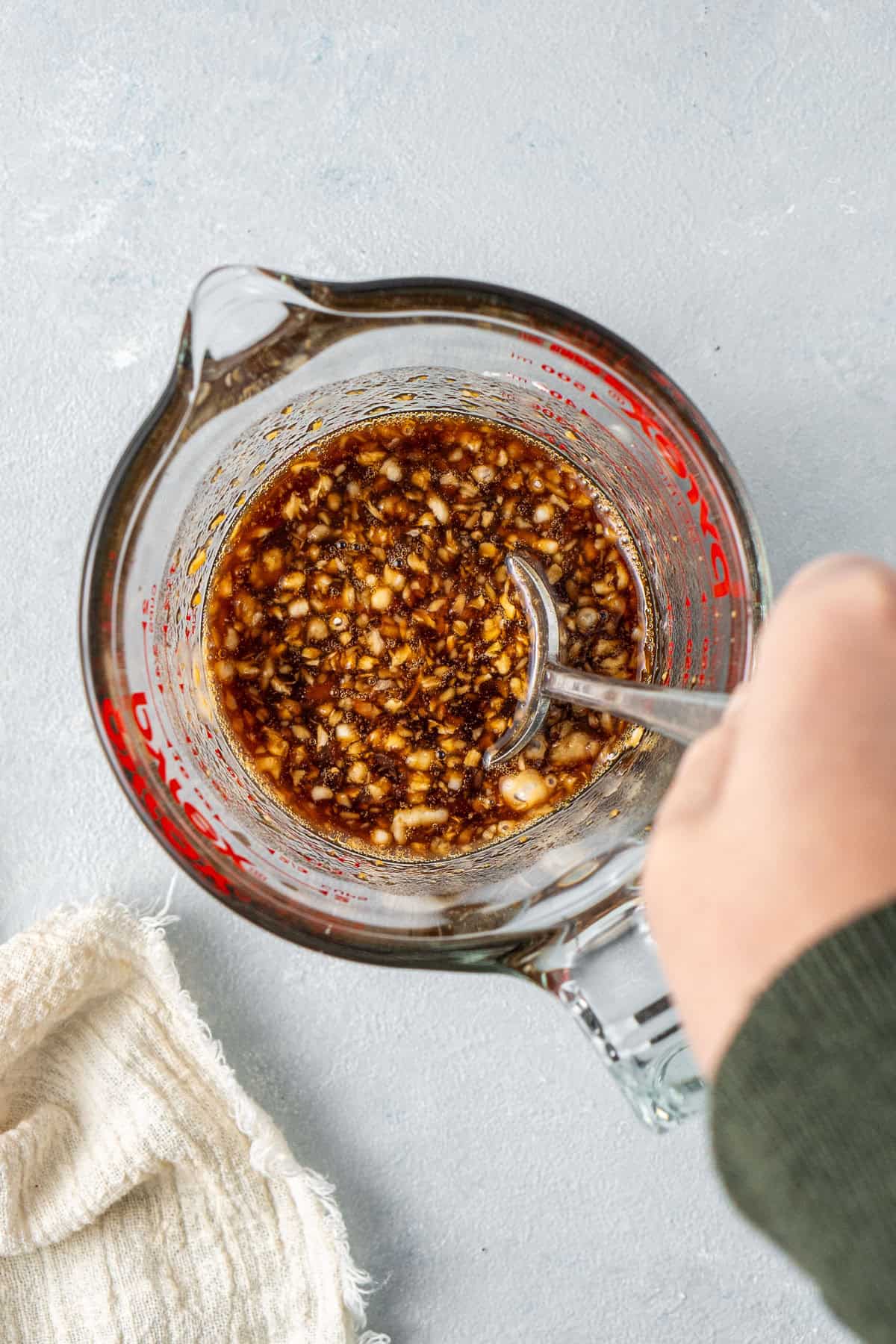 Mixing together the honey garlic sauce in a glass jug.