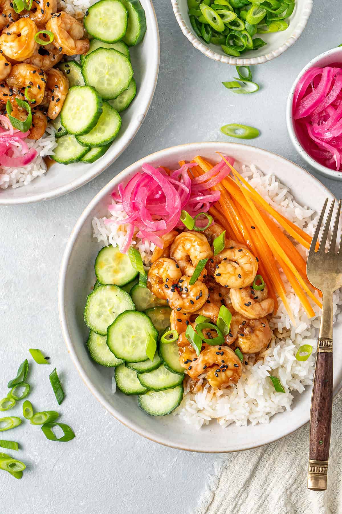 A colourful rice bowl with honey garlic prawns, pickled red onions, cucumber and carrot.