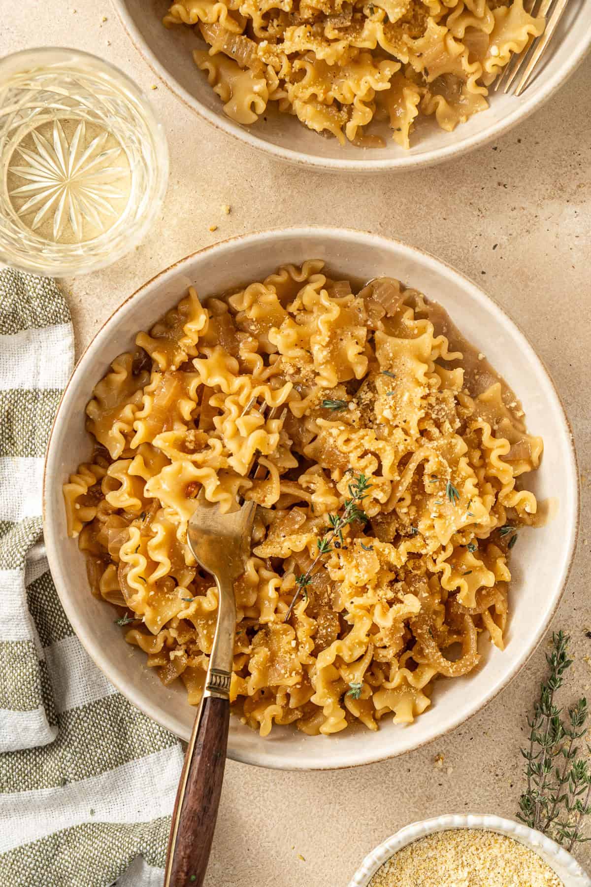 The served french onion pasta in bowls with a fork taking a bite.
