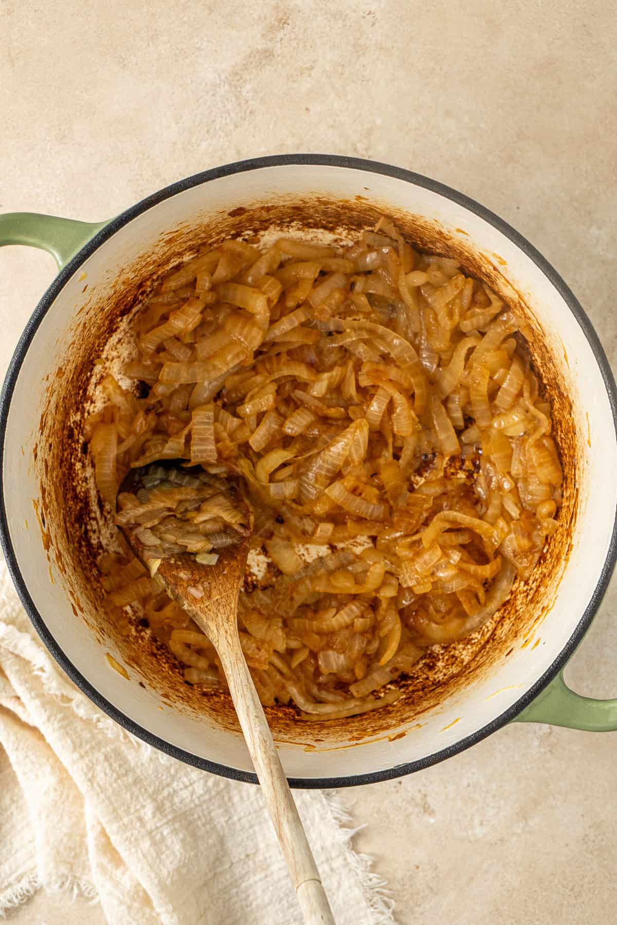 The caramelised onions in the pot with a wooden spoon.