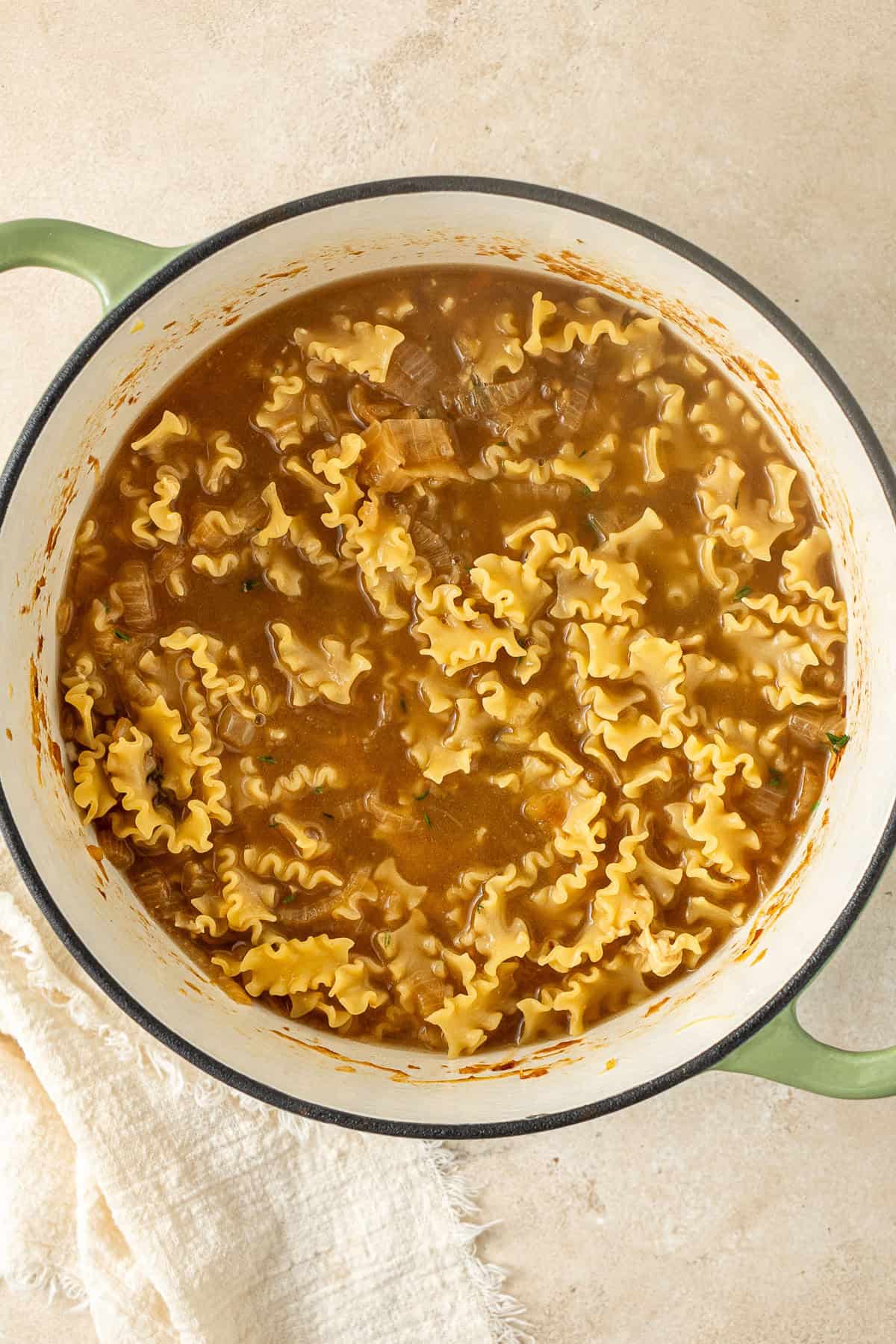 Adding the stock and pasta to the pot.