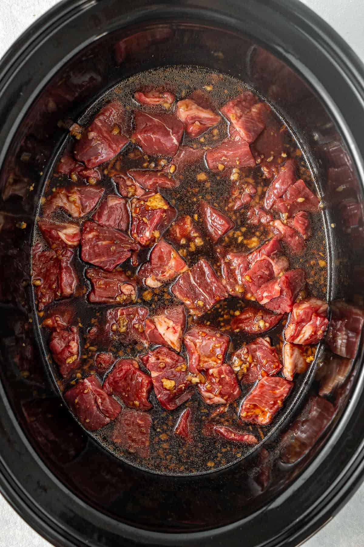The sauce poured over the beef in the slow cooker.