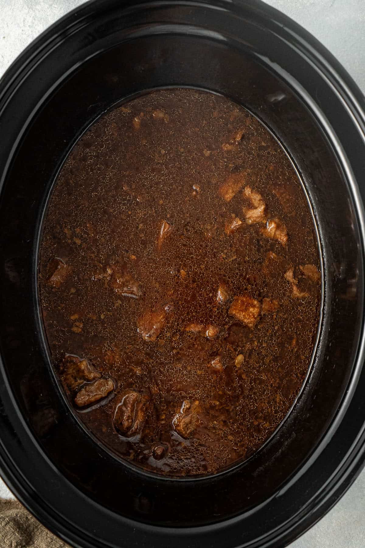 The cooked beef and sauce in the slow cooker.