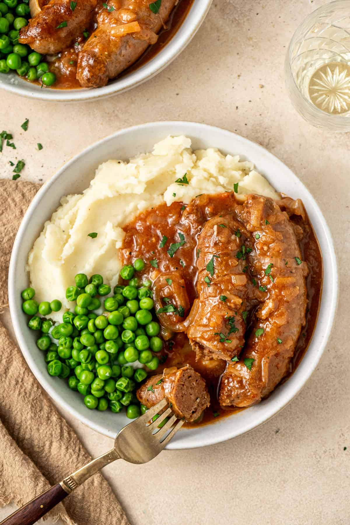 A sausage cut into on a plate of devilled sausages and mash.