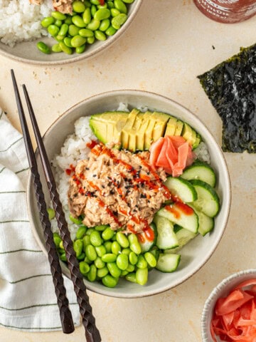Tuna sushi bowls with avocado and edamame with chopsticks.