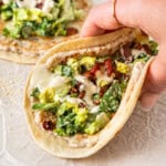 A hand holding a dairy free chicken caesar smash taco.