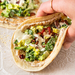 A hand holding a dairy free chicken caesar smash taco.