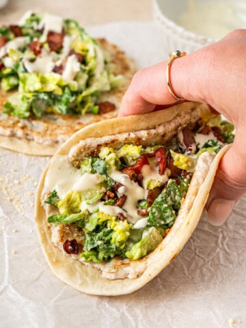 A hand holding a dairy free chicken caesar smash taco.
