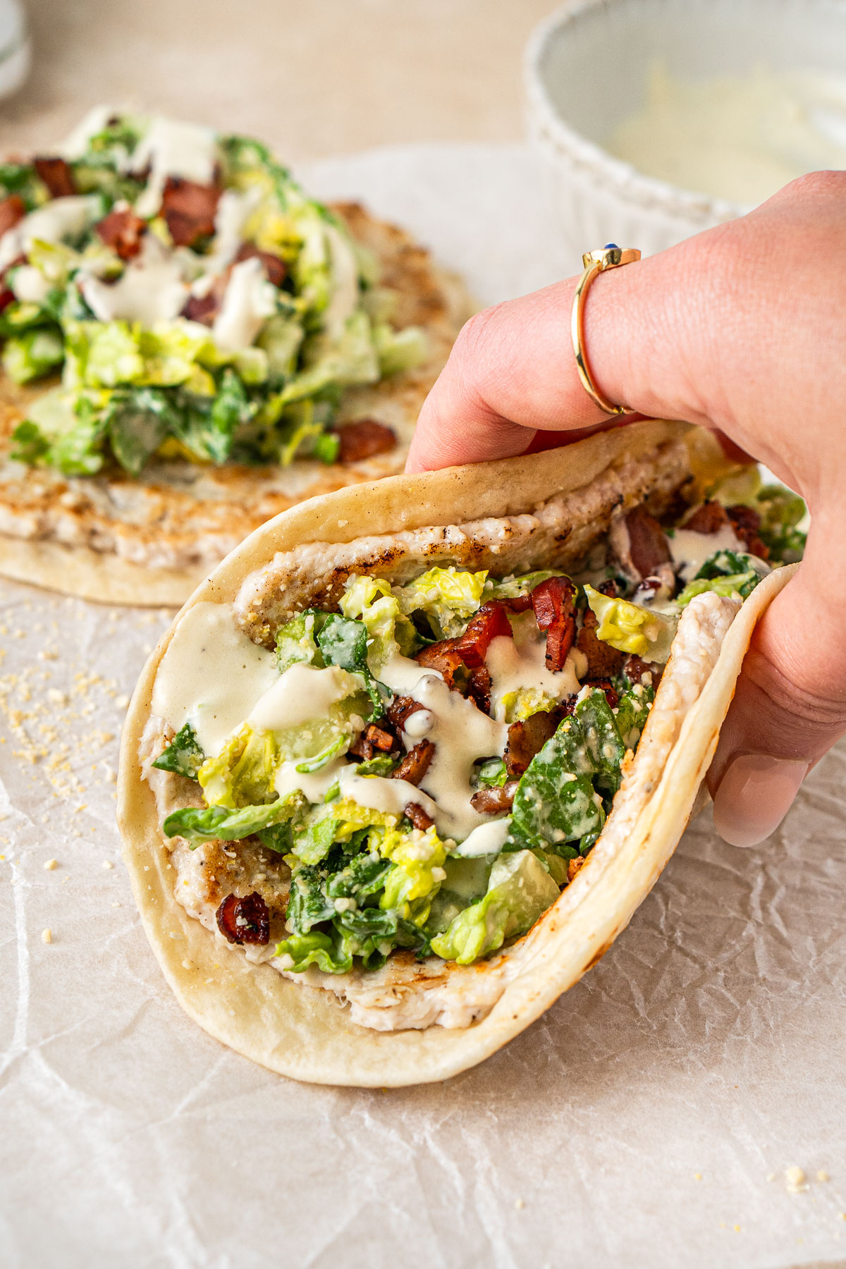 A hand holding a dairy free chicken caesar smash taco.