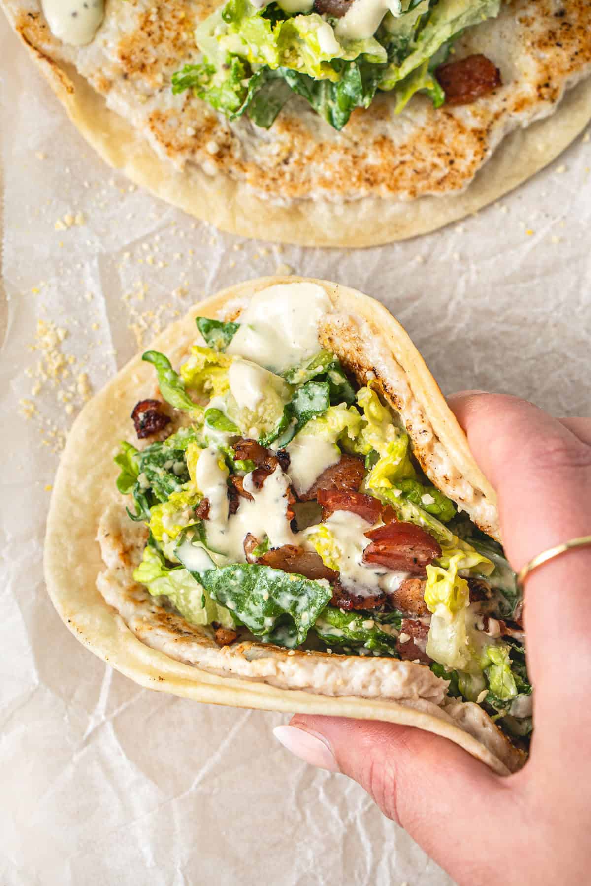 A hand holding a chicken caesar smash taco.