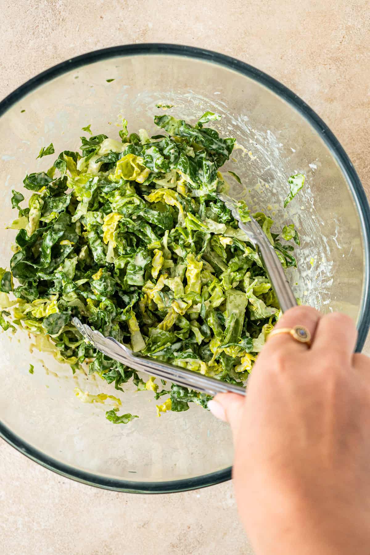 Tossing the caesar salad in a bowl.