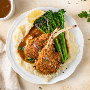 Two crumbed lamb cutlets on mashed potato with broccolini.
