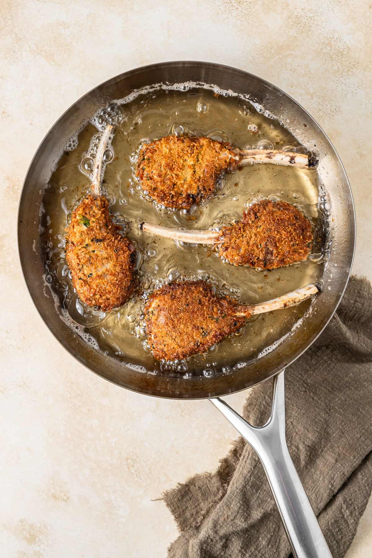 The crumbed cutlets frying in oil in a pan.