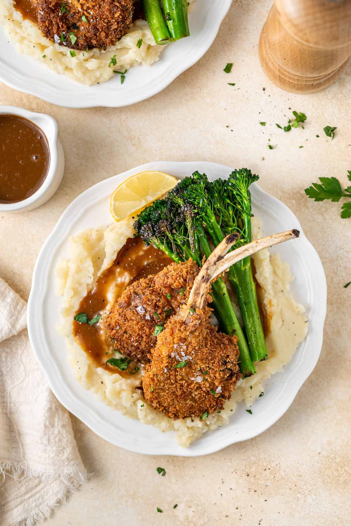 The cutlets on a plate with mash, gravy and broccolini.