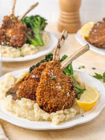 Two crumbed lamb cutlets on mashed potato with broccolini.