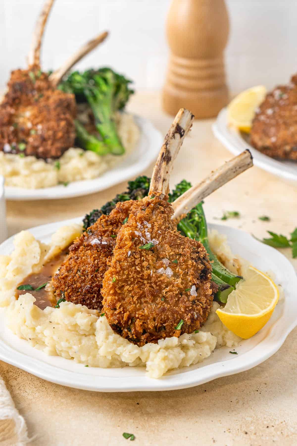 Two crumbed lamb cutlets on mashed potato with broccolini.