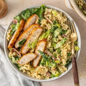 Dairy free chicken caesar salad served onto a plate with slices of chicken schnitzel.