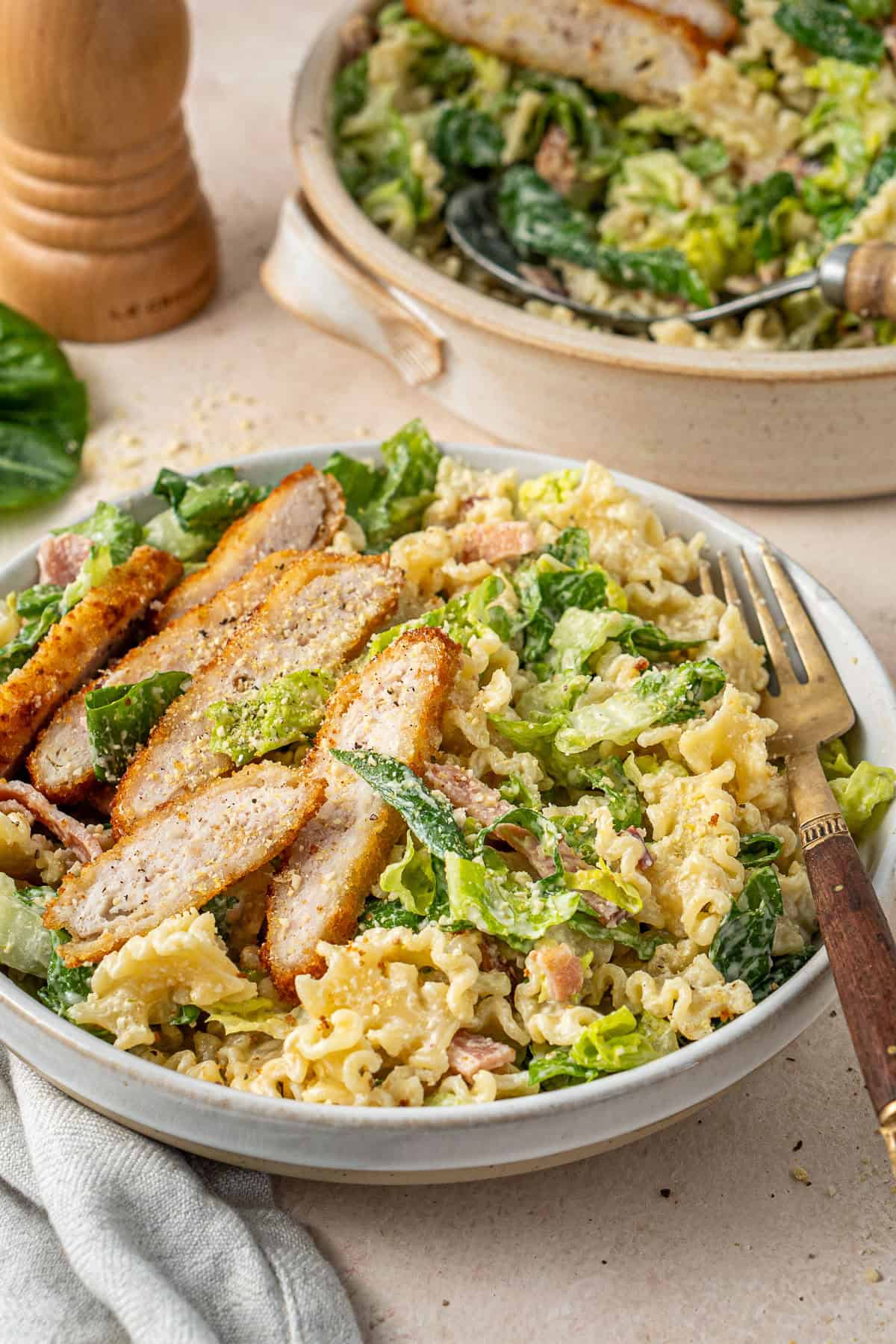 The caesar pasta salad with chicken served into plates.