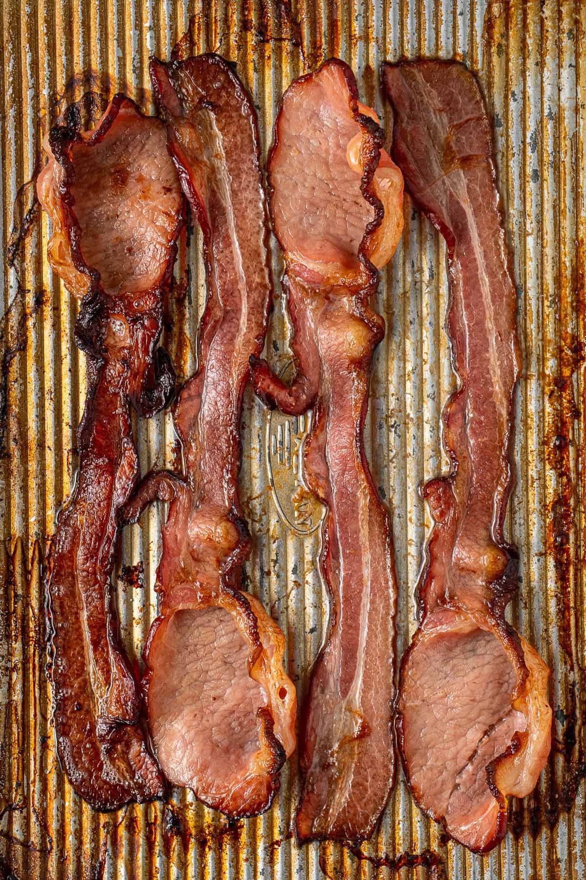 The crispy bacon cooked on a baking tray.