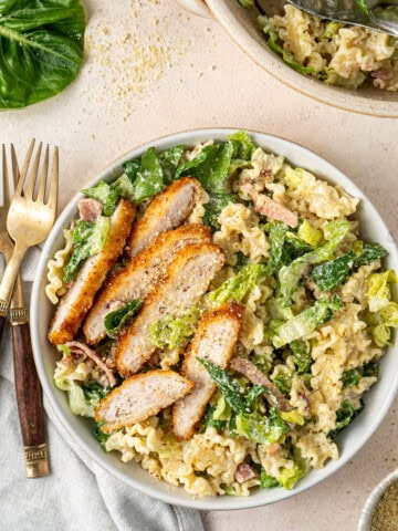 Dairy free chicken caesar salad served onto a plate with slices of chicken schnitzel.