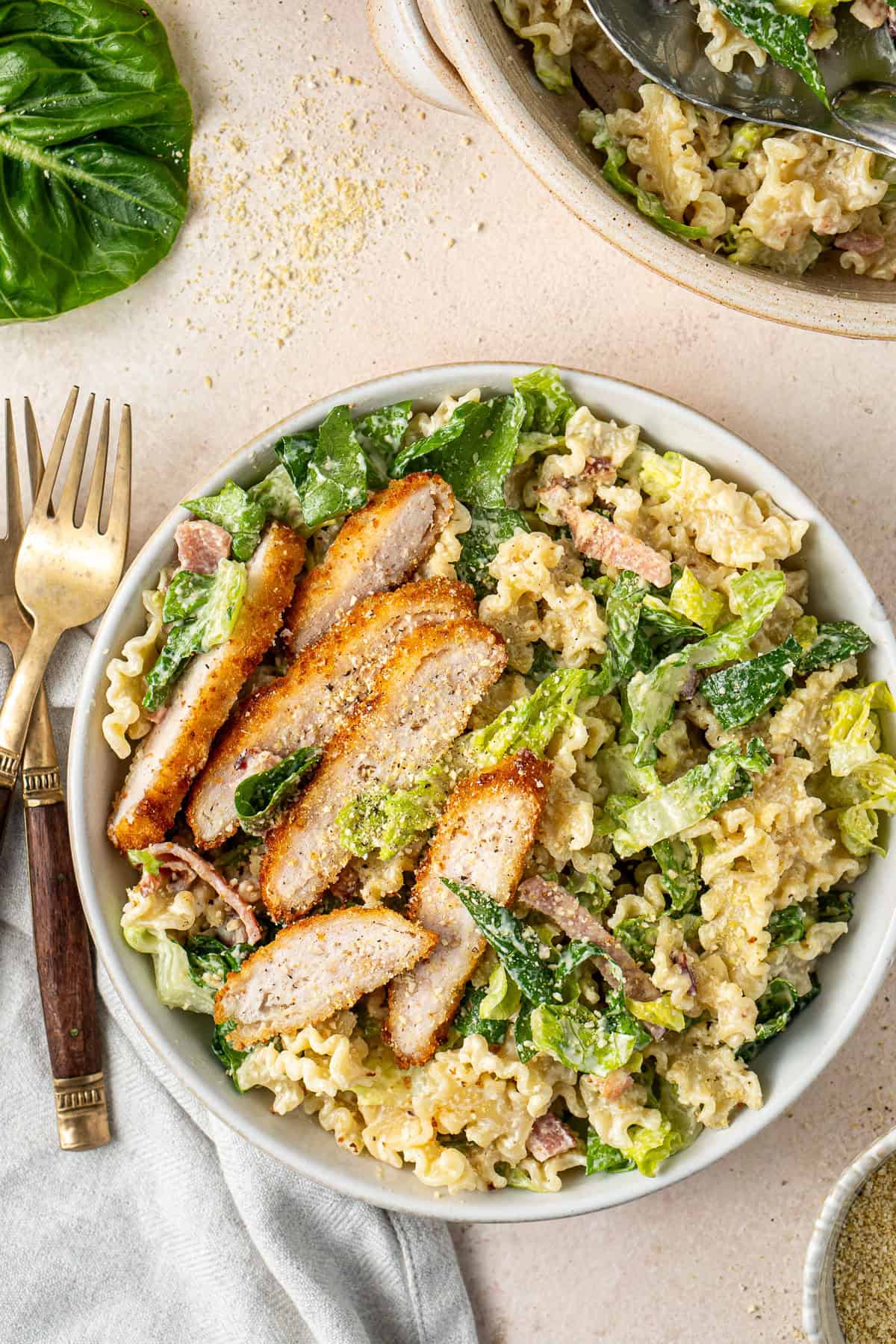 Dairy free chicken caesar salad served onto a plate with slices of chicken schnitzel. 