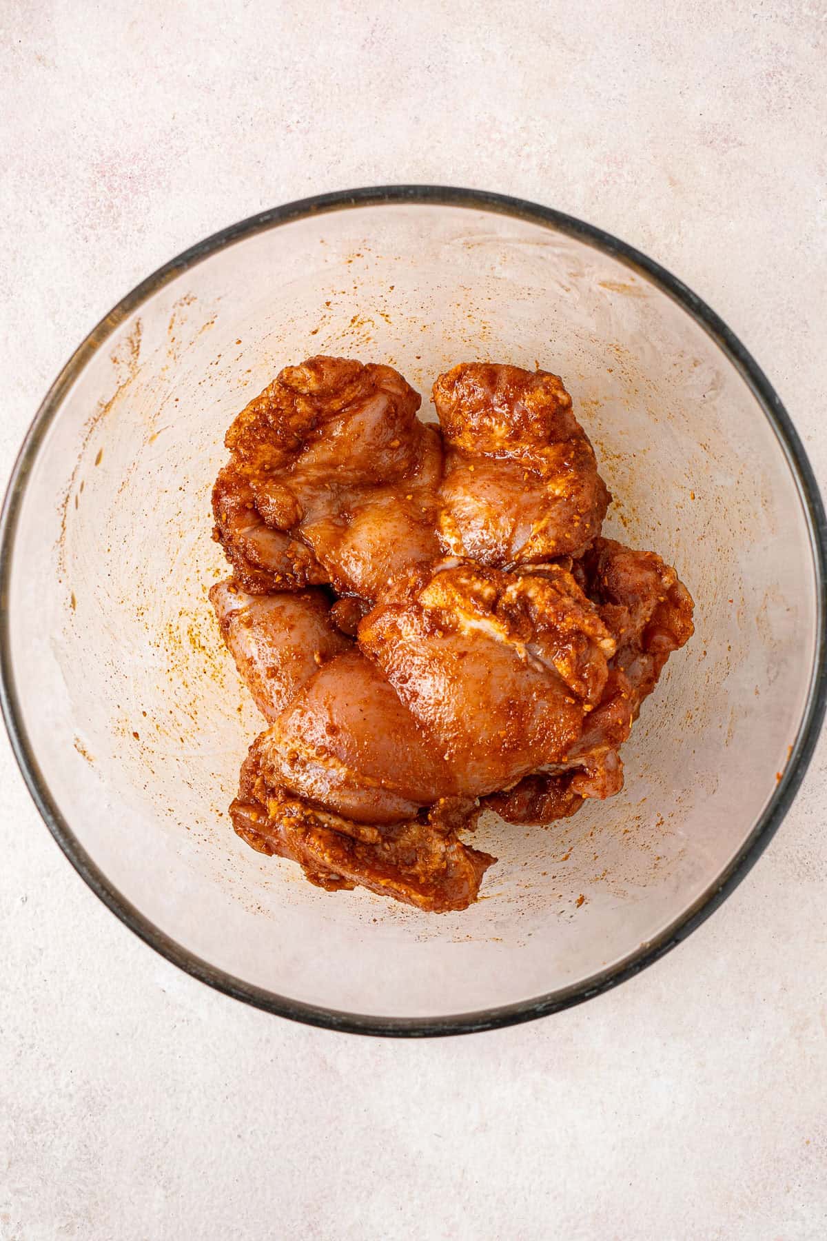 The raw chicken in a mixing bowl with taco seasoning.