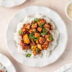 Sweet chilli tofu with rice on white plates with spring onion.