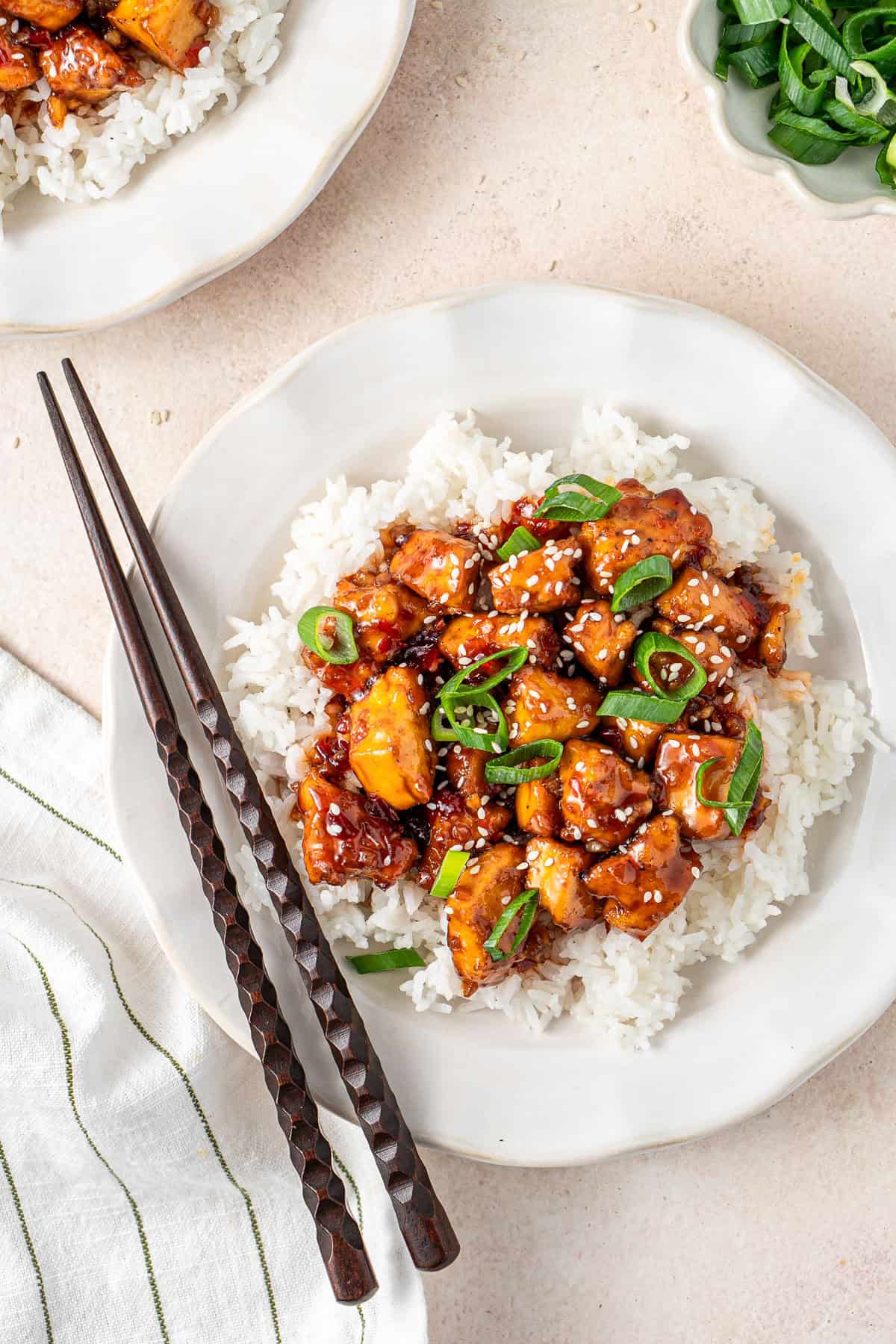 The sweet chilli tofu on a pate with rice and chopsticks.