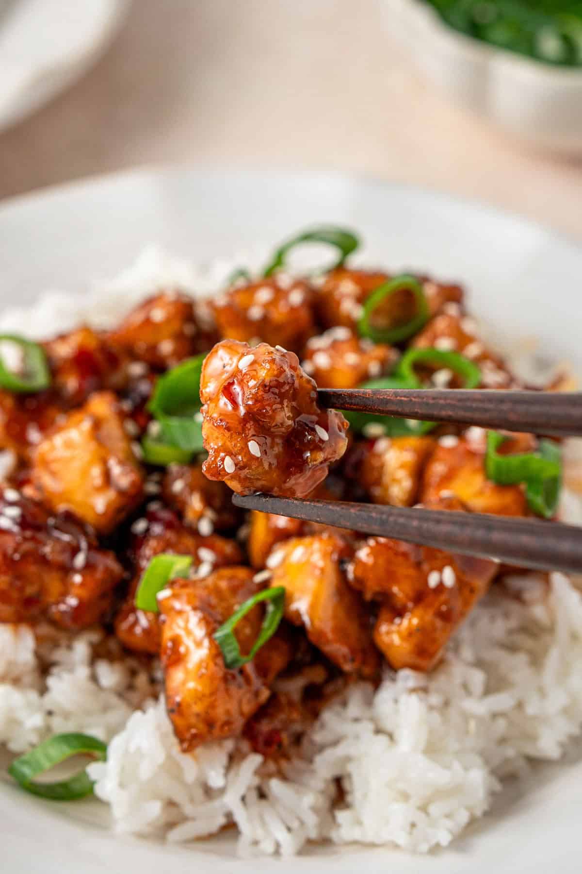 A close up of a piece of tofu being held up with chopsticks.